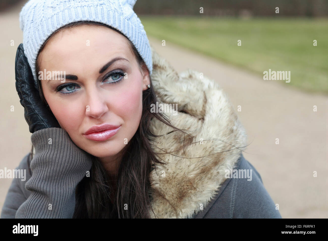 Outdoor portrait of beautiful attractive young brunette woman in warm fur lined winter jacket or coat gloves and hat looking away into distance  Model Release: Yes.  Property release: No. Stock Photo