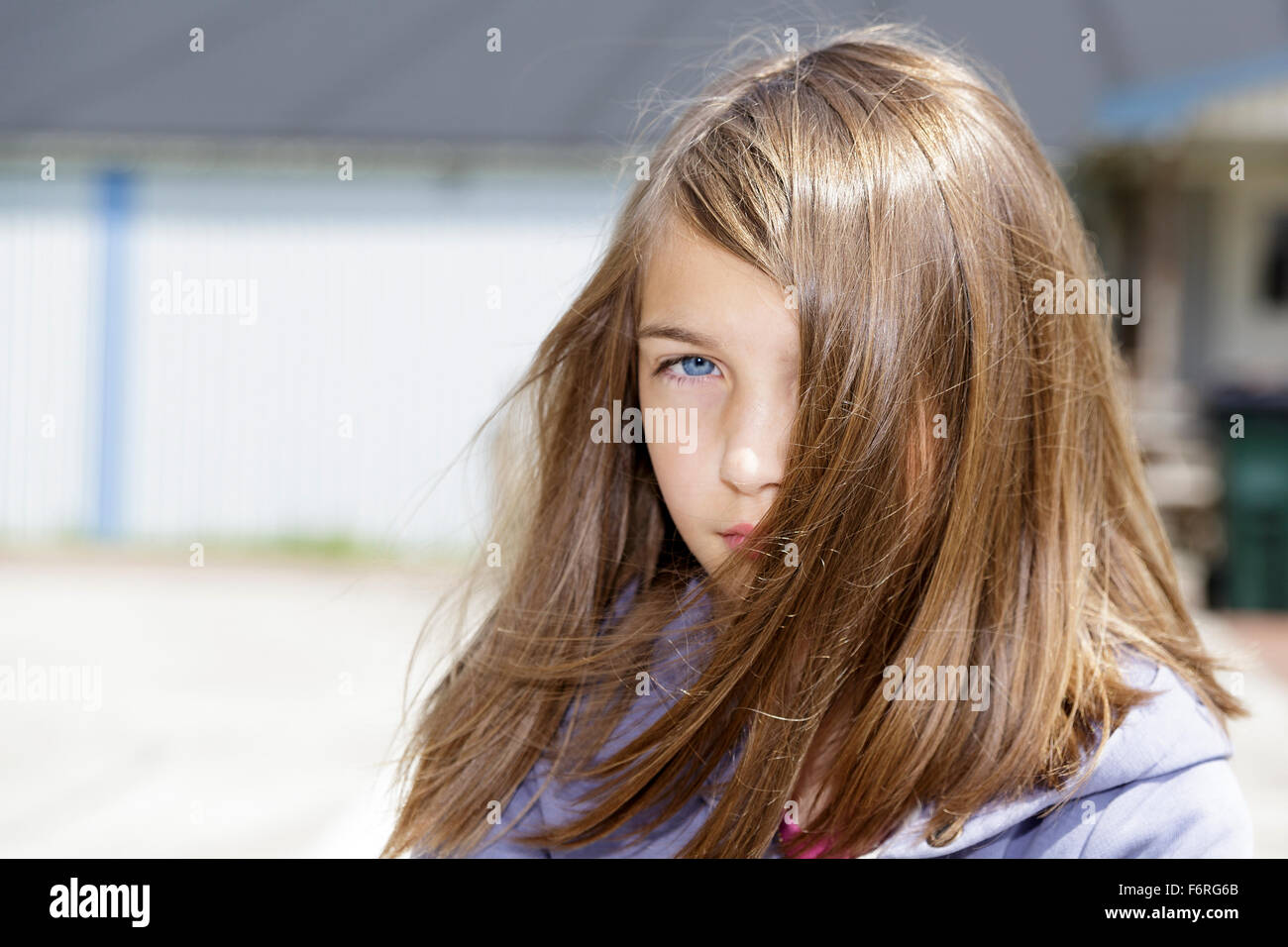 Young brunette long hair pre-adolecsent girl looking at camera with an attitude portrait outdoors  Model Release: Yes.  Property Release: No. Stock Photo