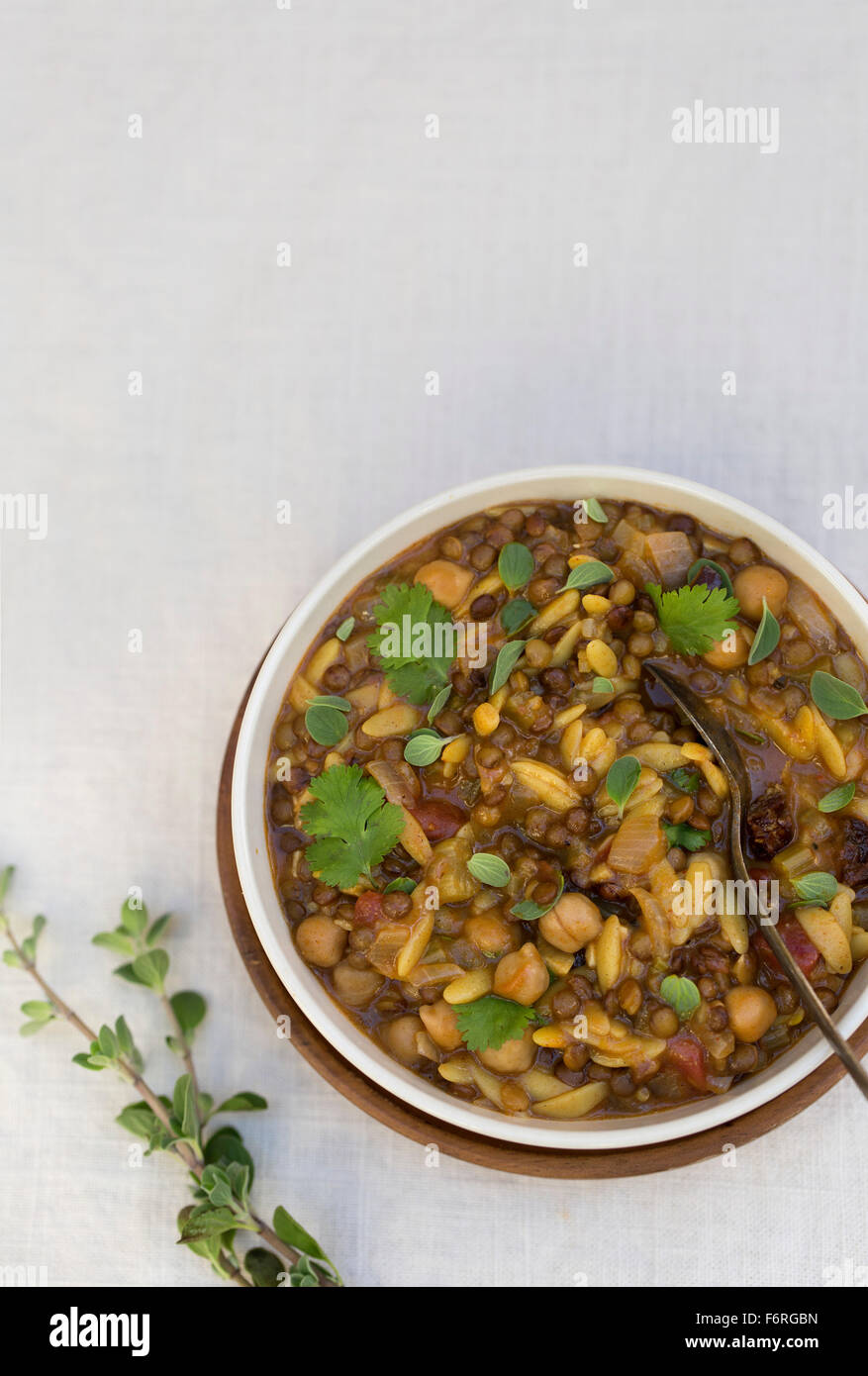 A bowl of harira garnished with fresh cilantro and marjoram is photographed from the top. Stock Photo