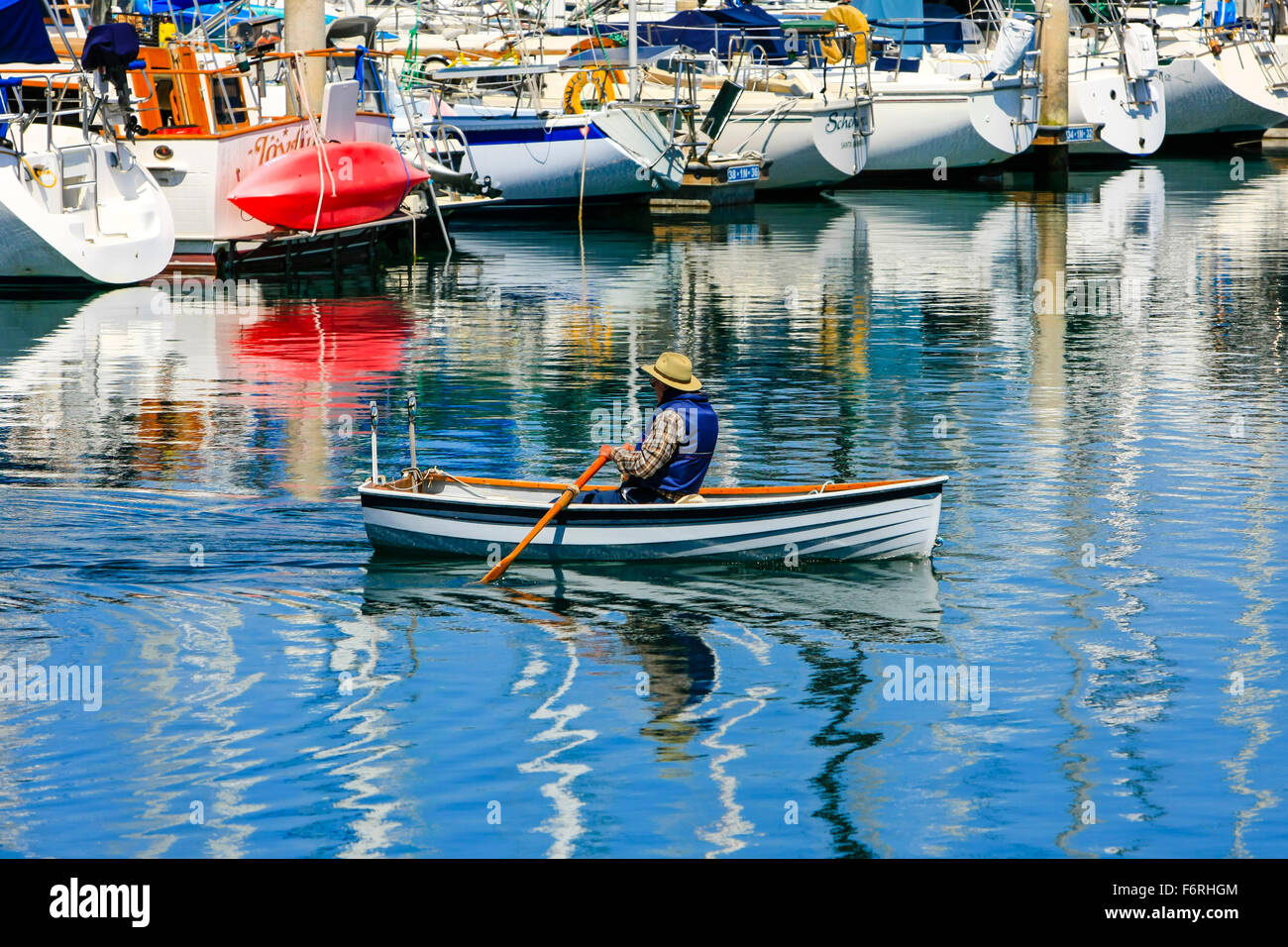 A lone man rowing his boat around Santa Barbara harbor and marina in California Stock Photo