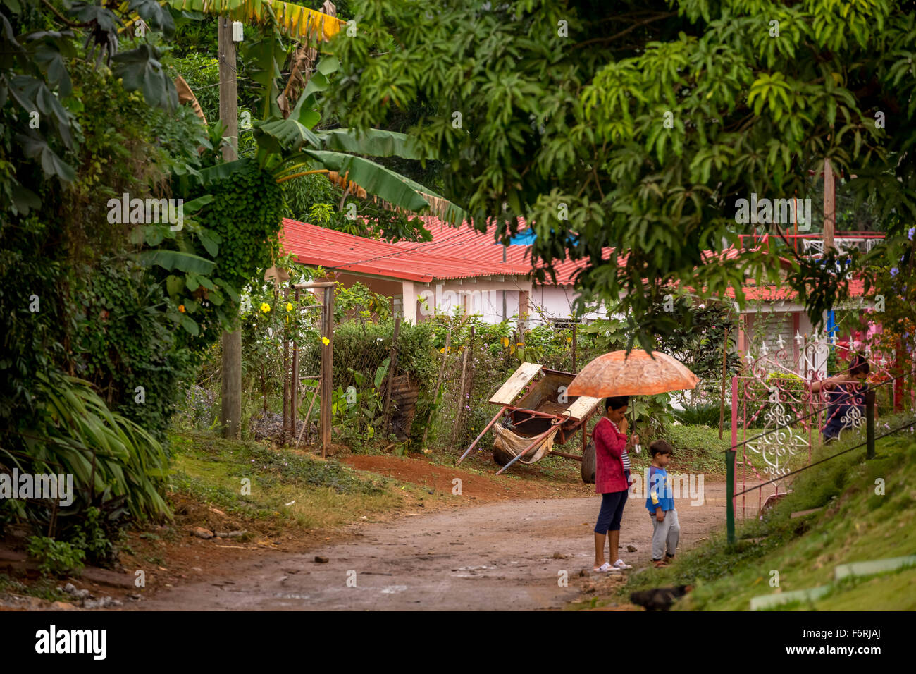Street scene with his wife and child and umbrella, clay road, Viñales, Cuba, Pinar del Río, Cuba Stock Photo