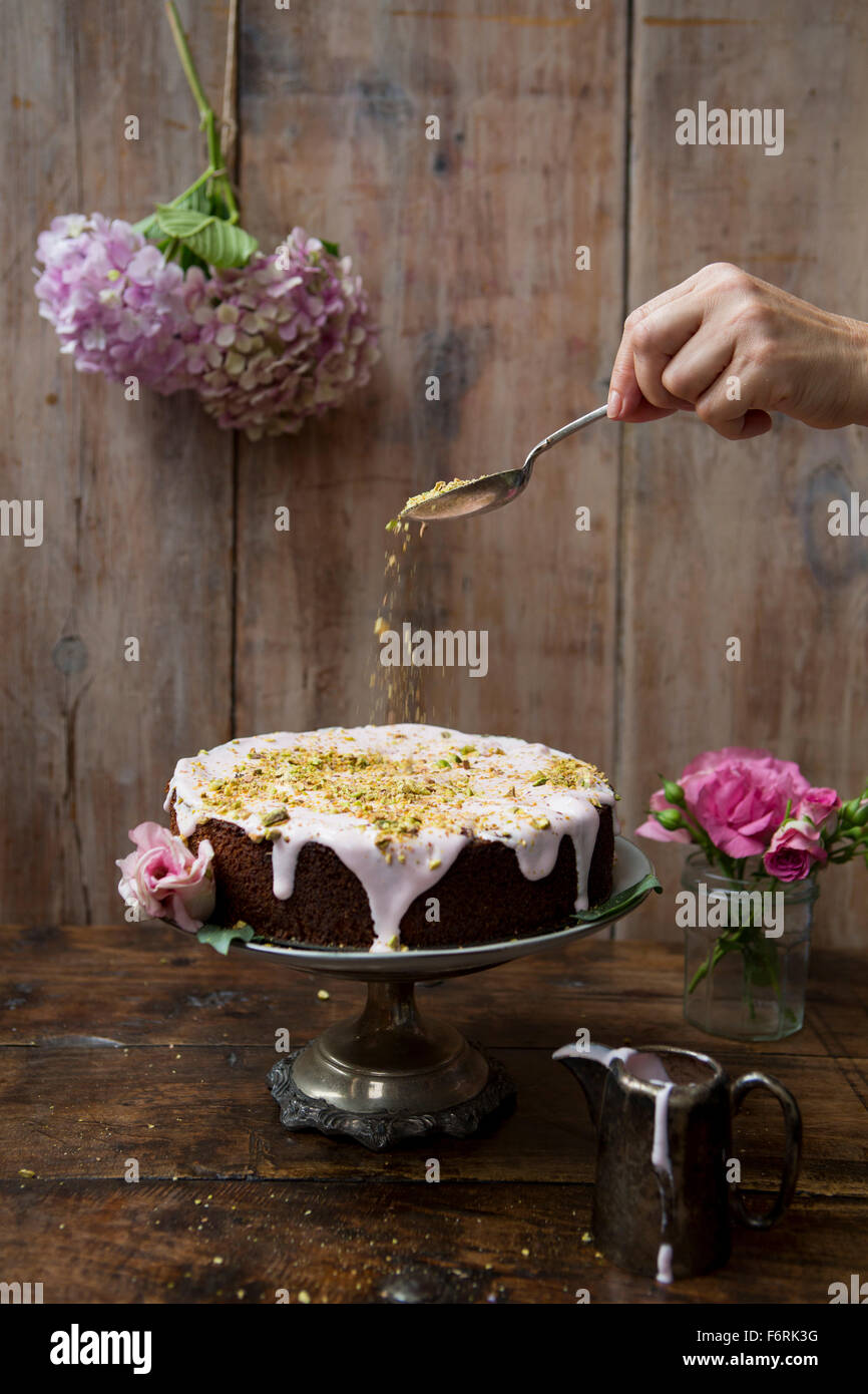Pistachio and Rose Cake with Hand Sprinkling Nuts Stock Photo