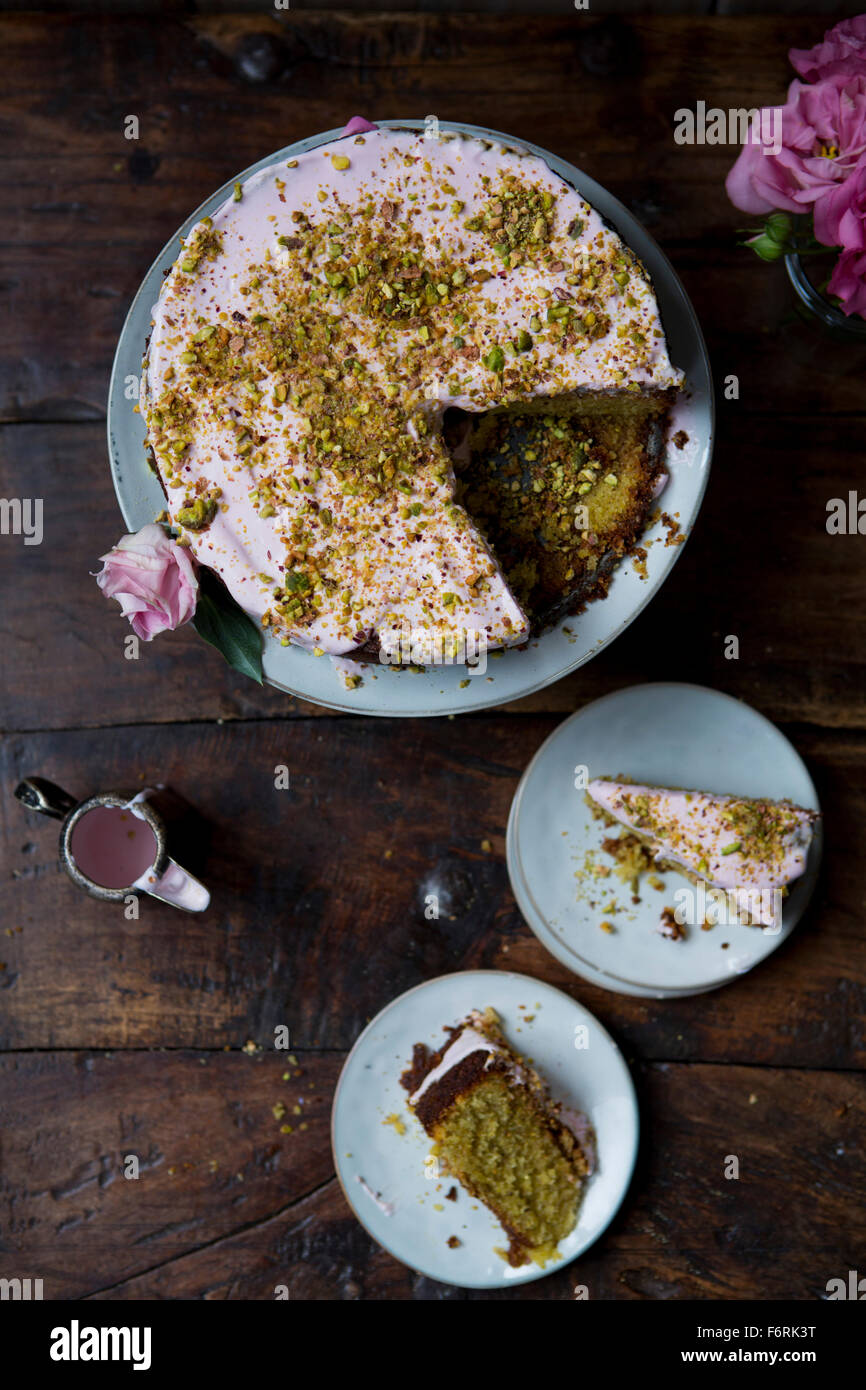 Pistachio and Rose Cake, Sliced to Serve with Jug of Icing Stock Photo