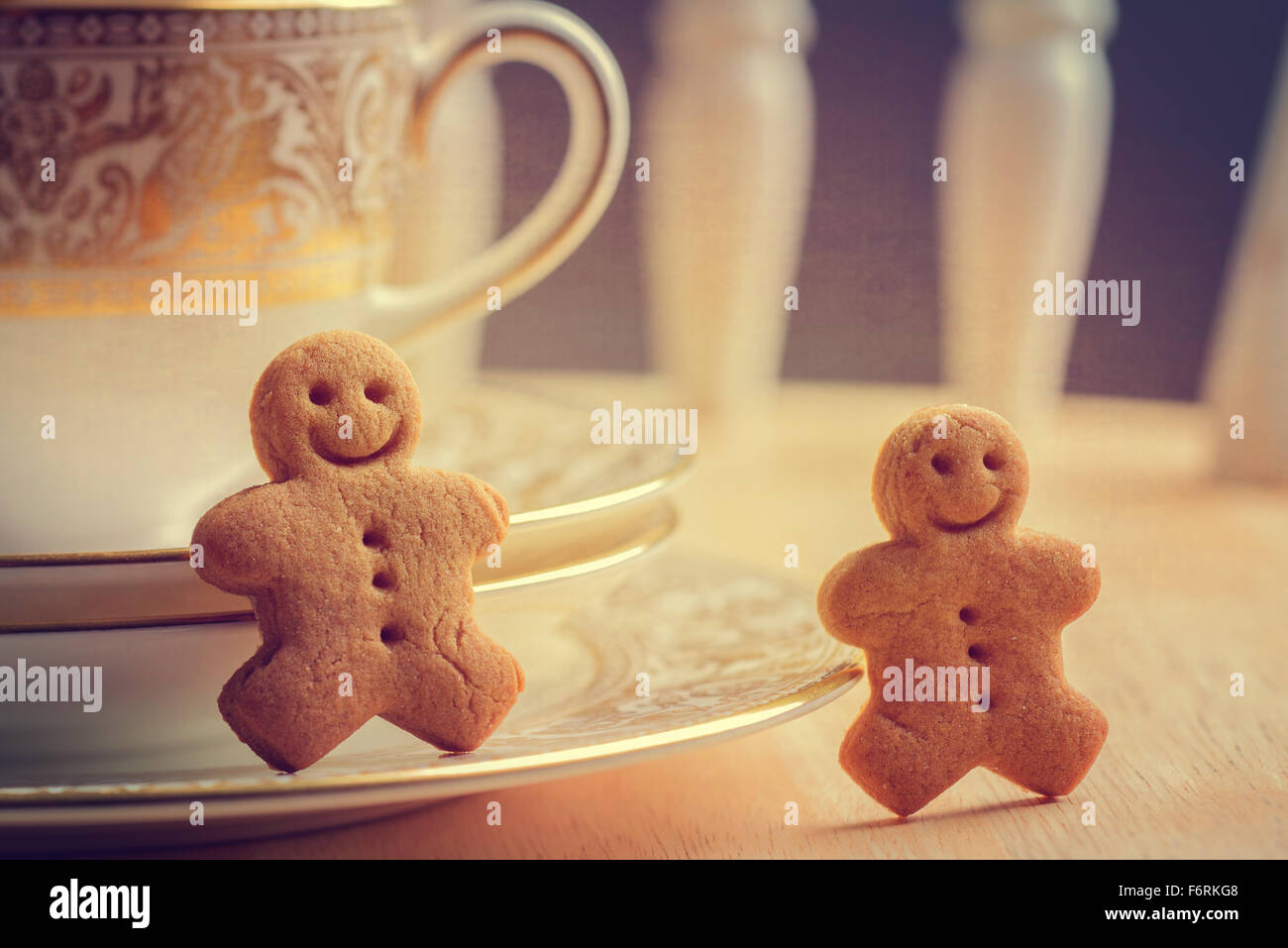Happy gingerbread men sitting with antique teacups and saucers Stock Photo