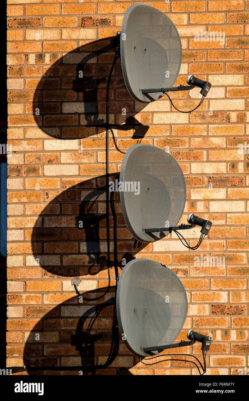 Three Sky TV digital Satellite dishes together attached vertically above each other on a modern house wall in Dundee, UK Stock Photo