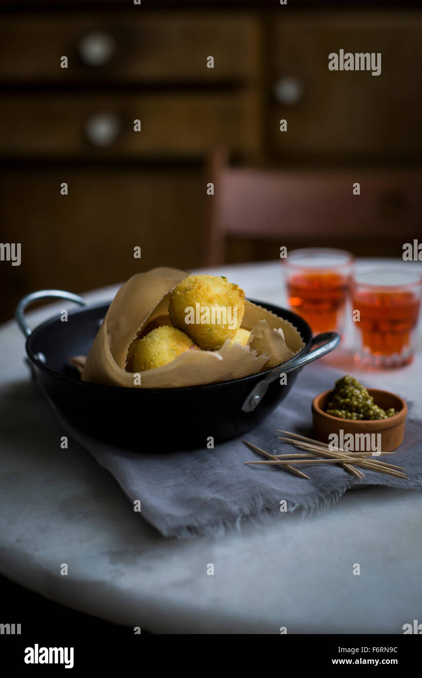 Cheese balls with herbal mustard on marble table with vintage kitchen cupboard in background Stock Photo