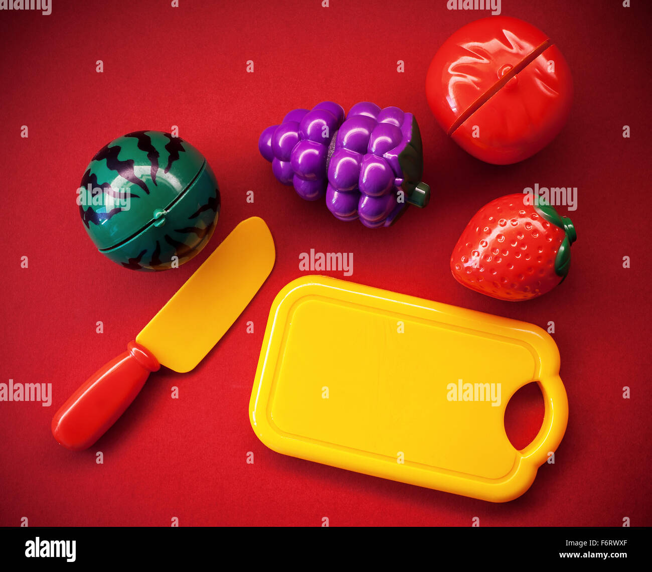 Plastic fruits and vegetables as toys, on red background. Stock Photo