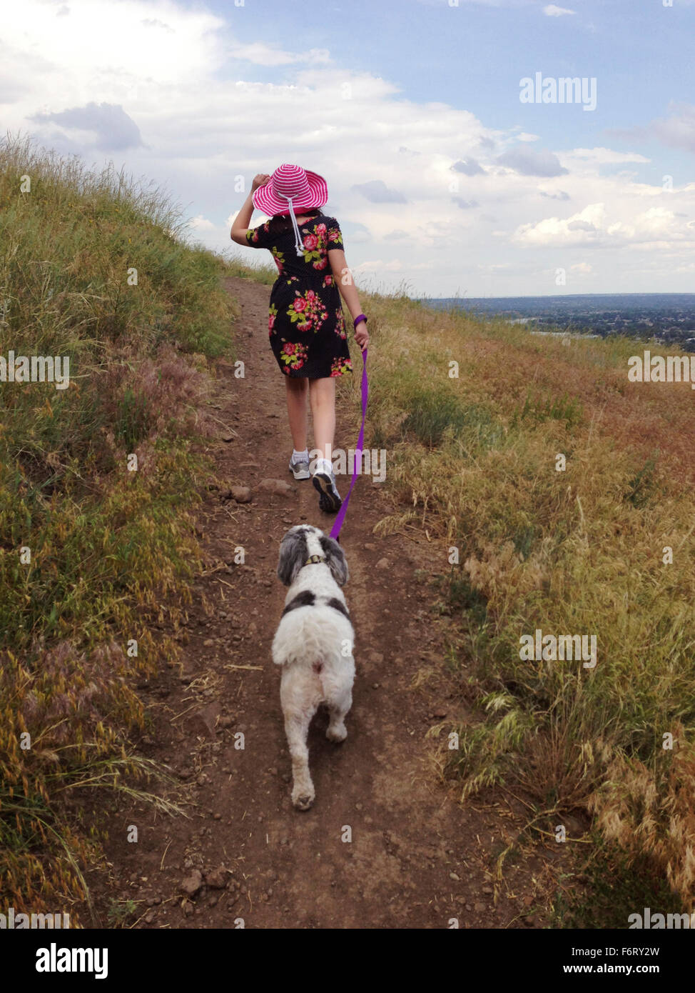 Woman walking dog on hill path Stock Photo
