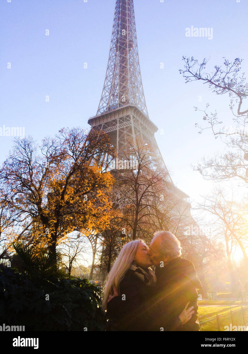 Caucasian couple kissing under Eiffel Tower, Paris, Ile - Smartphone Captured Stock Image