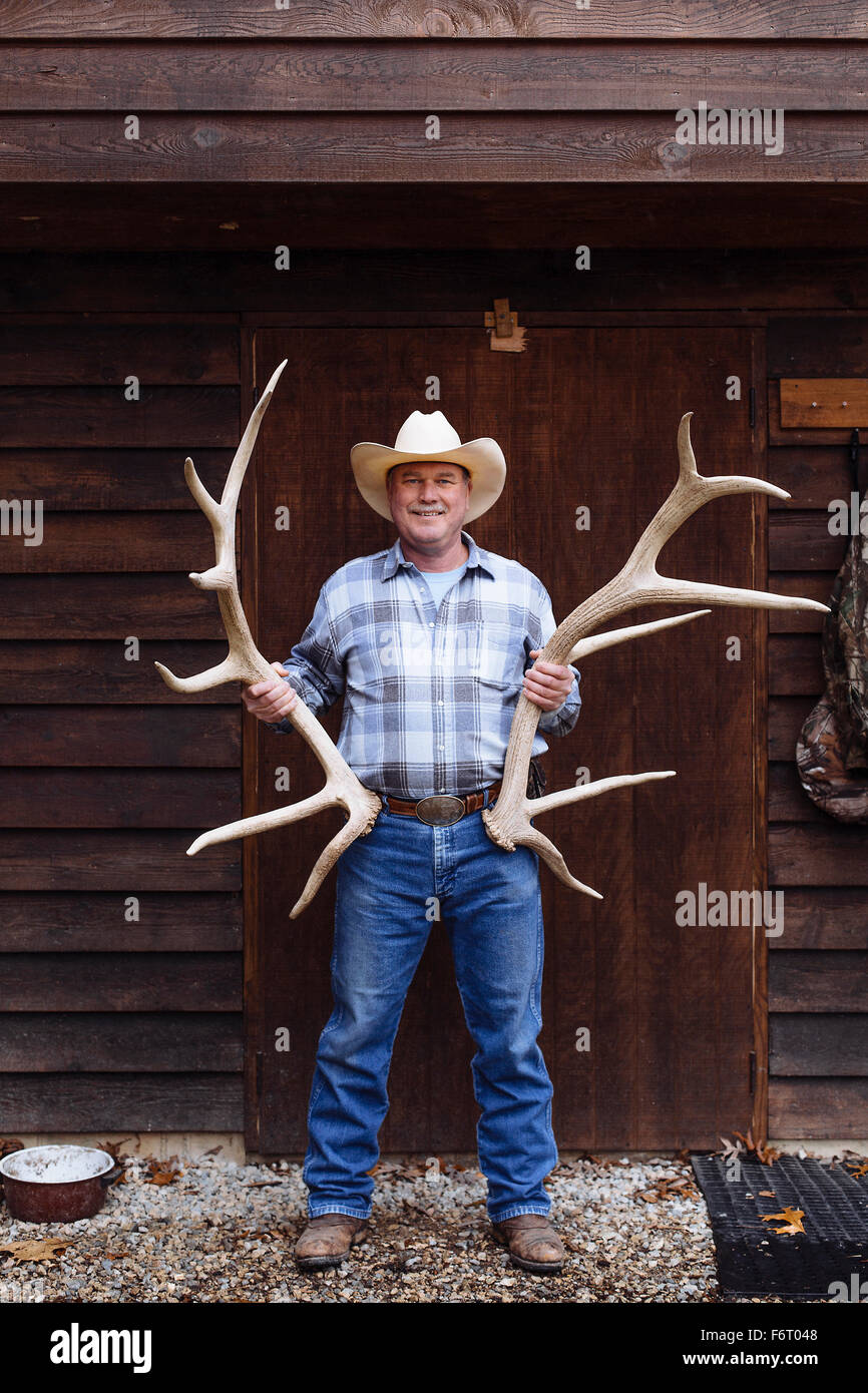 Caucasian farmer holding antlers on front porch Stock Photo