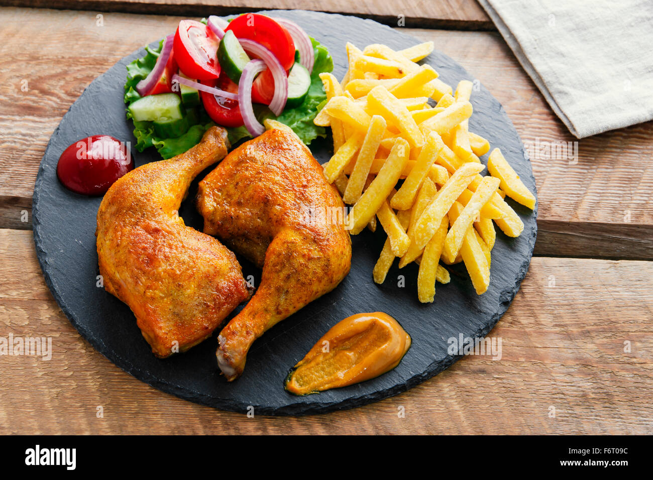 roasted chicken legs with french fries and salad Stock Photo - Alamy
