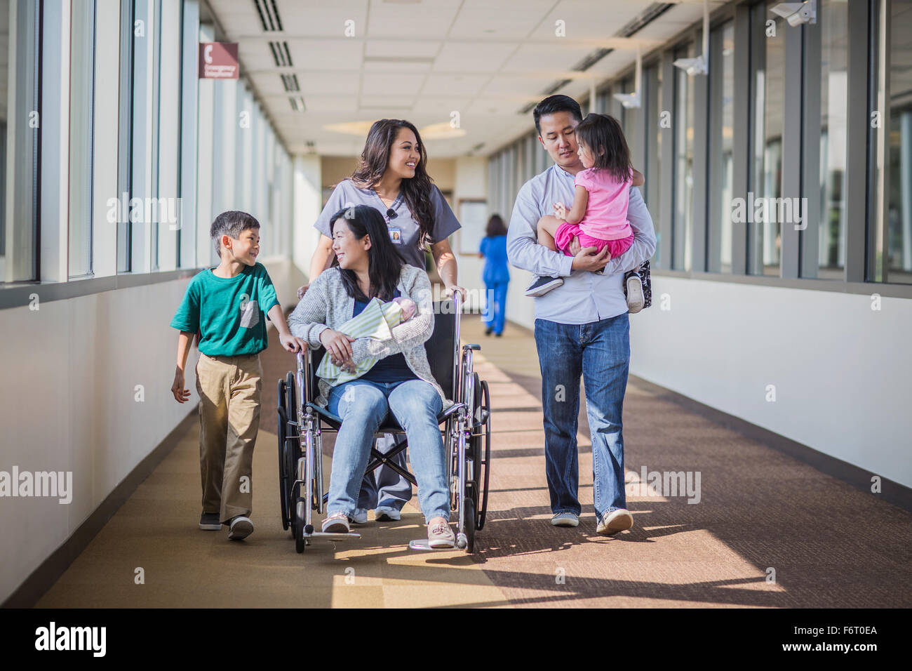 Nurse with patient and family in hospital hallway Stock Photo