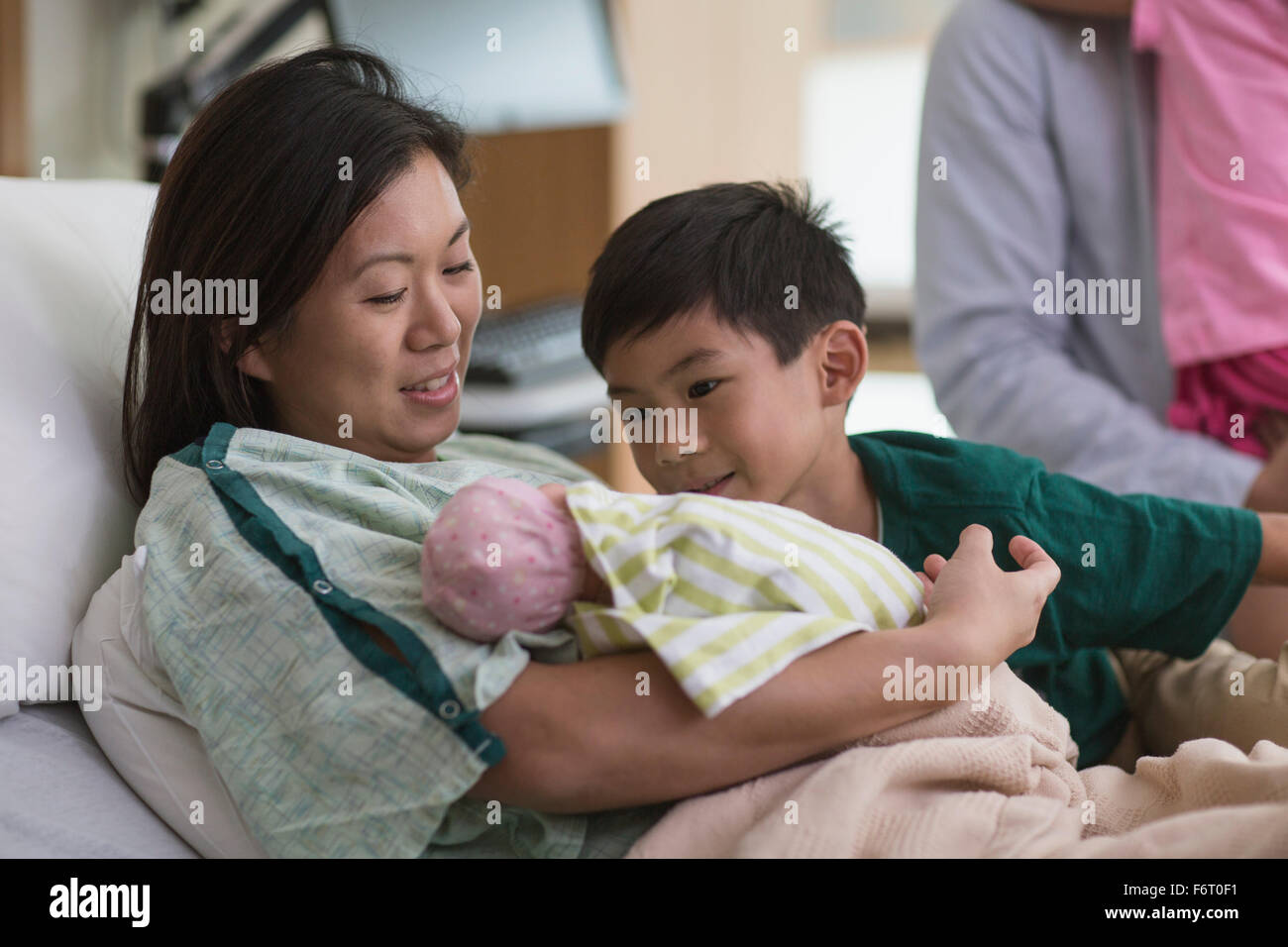 Family admiring newborn baby in hospital room Stock Photo
