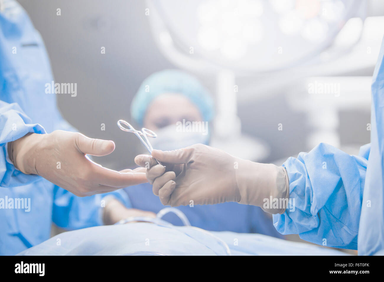 Surgeons handing forceps in operating room Stock Photo