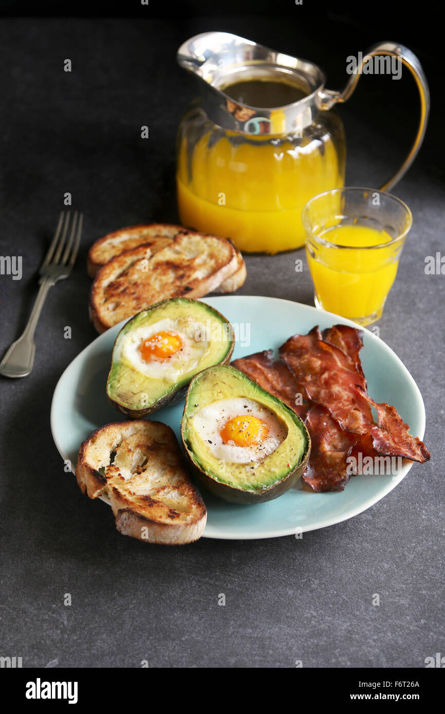 Breakfast with eggs baked in avocado,bacon ,bread toast and orange juice Stock Photo