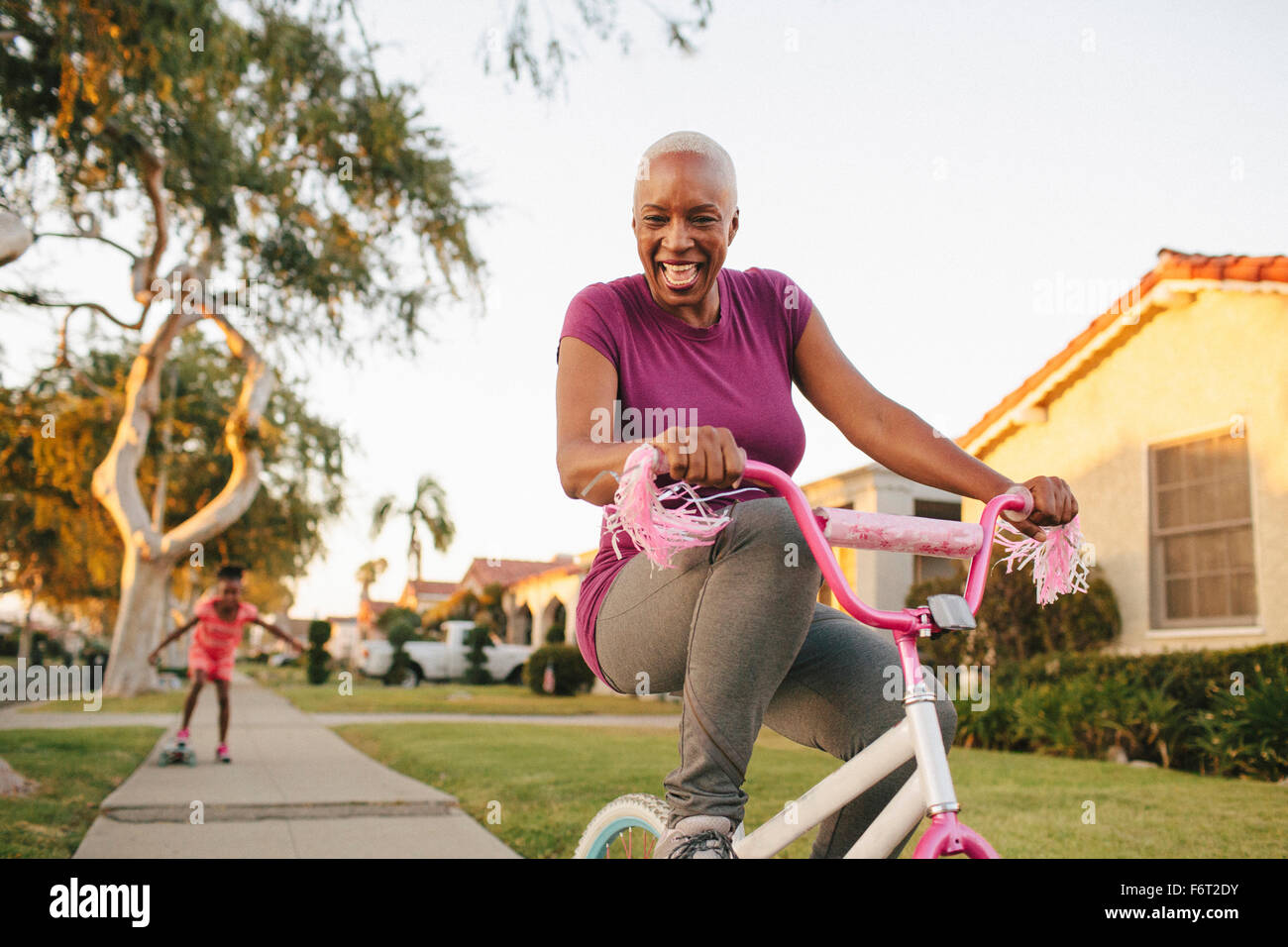 Mother and daughter riding skateboard and bicycle Stock Photo