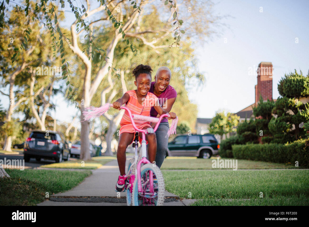 Mother pushing daughter on bicycle Stock Photo
