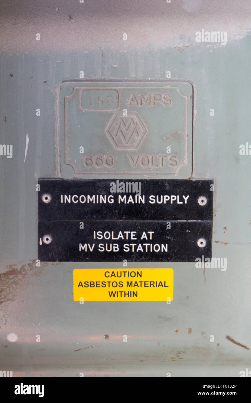 Old electricity switch panel with asbestos warning label Stock Photo