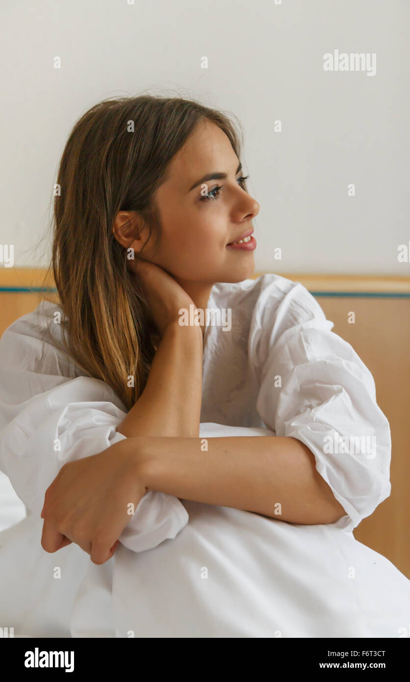 Caucasian woman sitting on bed Stock Photo