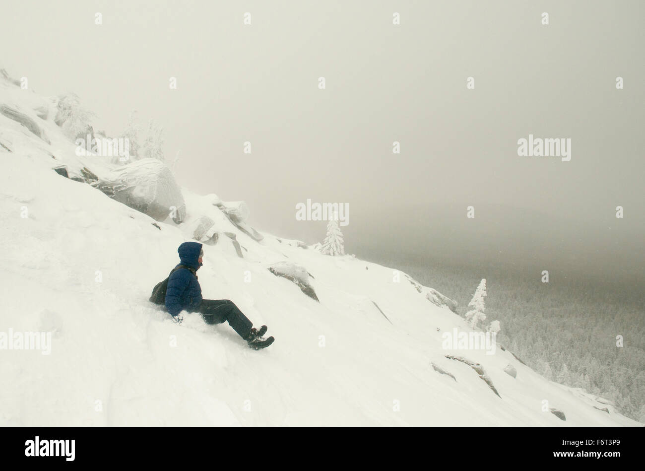 Caucasian man sledding on snowy mountain Stock Photo