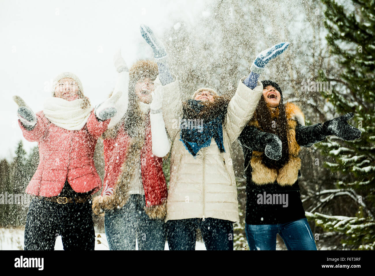 Caucasian girls tossing snow in air Stock Photo