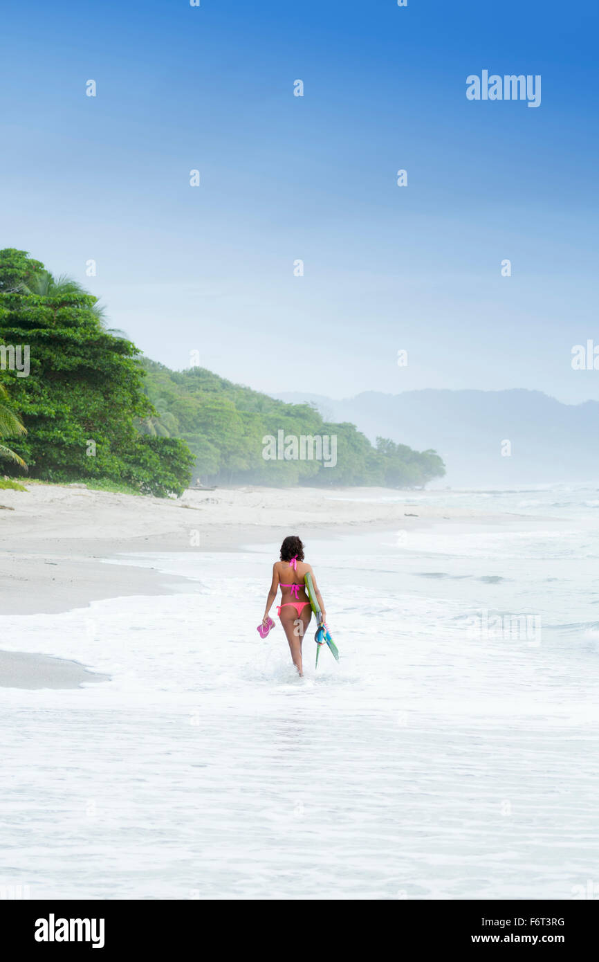 Hispanic woman carrying fins on beach Stock Photo