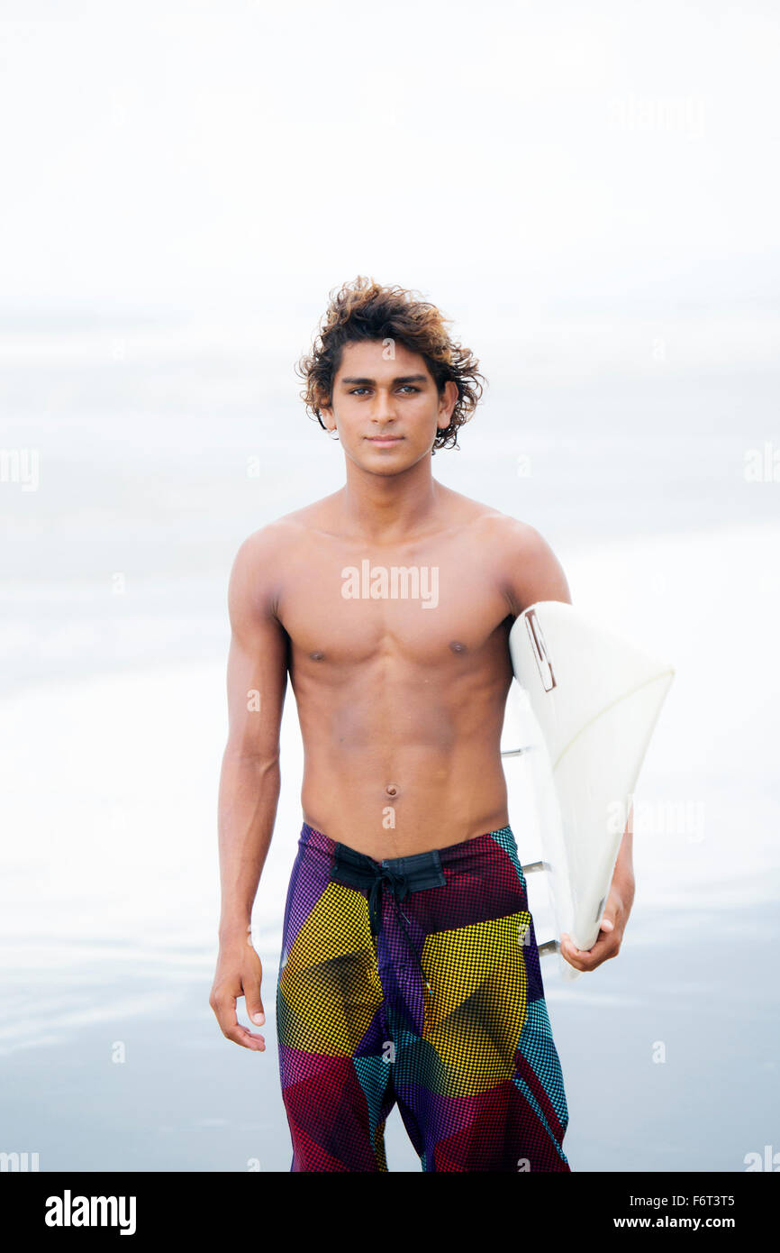 Man carrying surfboard on beach Stock Photo