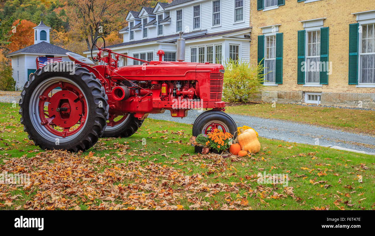 A bright red tractor in front of a house in Woodstock, Vermont Stock