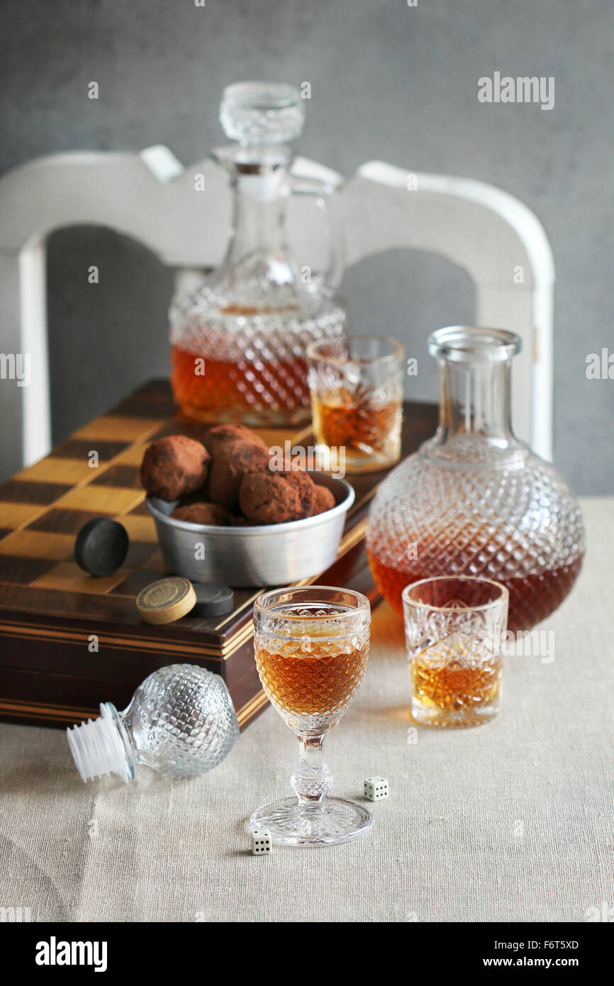 Still life with glasses and bottles of liqueur and backgammon on a table Stock Photo