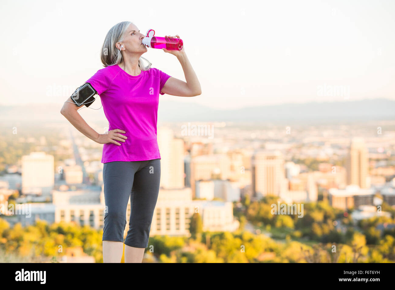 Caucasian woman drinking water bottle on urban hilltop Stock Photo