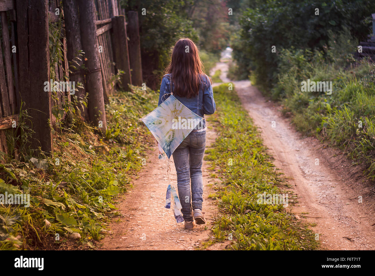 Caucasian teenage girl carrying kite on dirt road Stock Photo