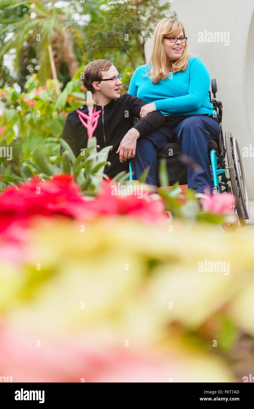 Man and paraplegic girlfriend exploring garden Stock Photo