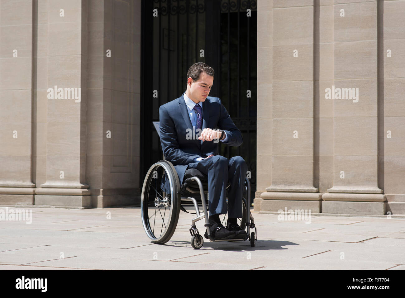 Paraplegic businessman in wheelchair checking watch Stock Photo