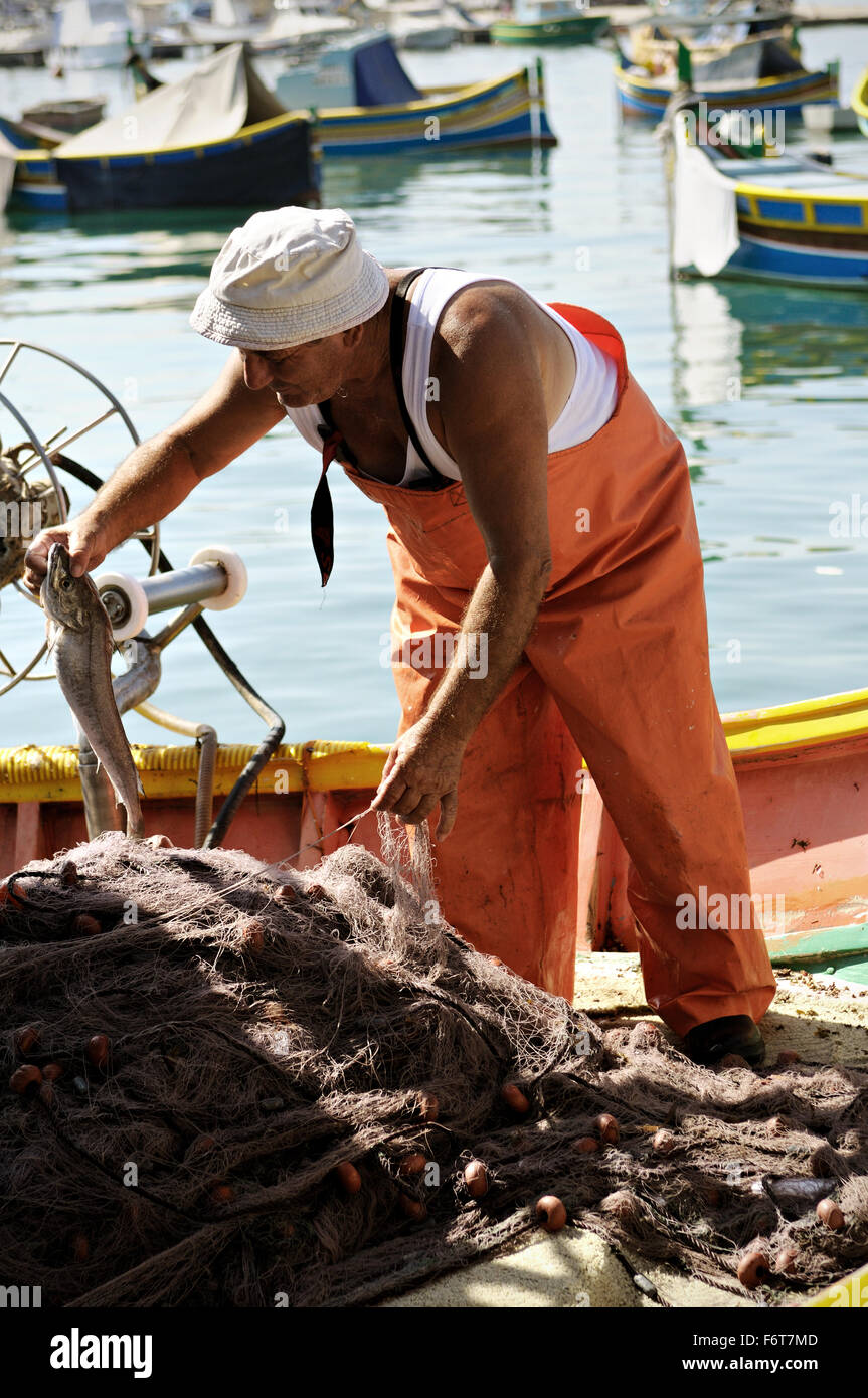 Maltese fisherman taking out fish from fishing net on a boat in the