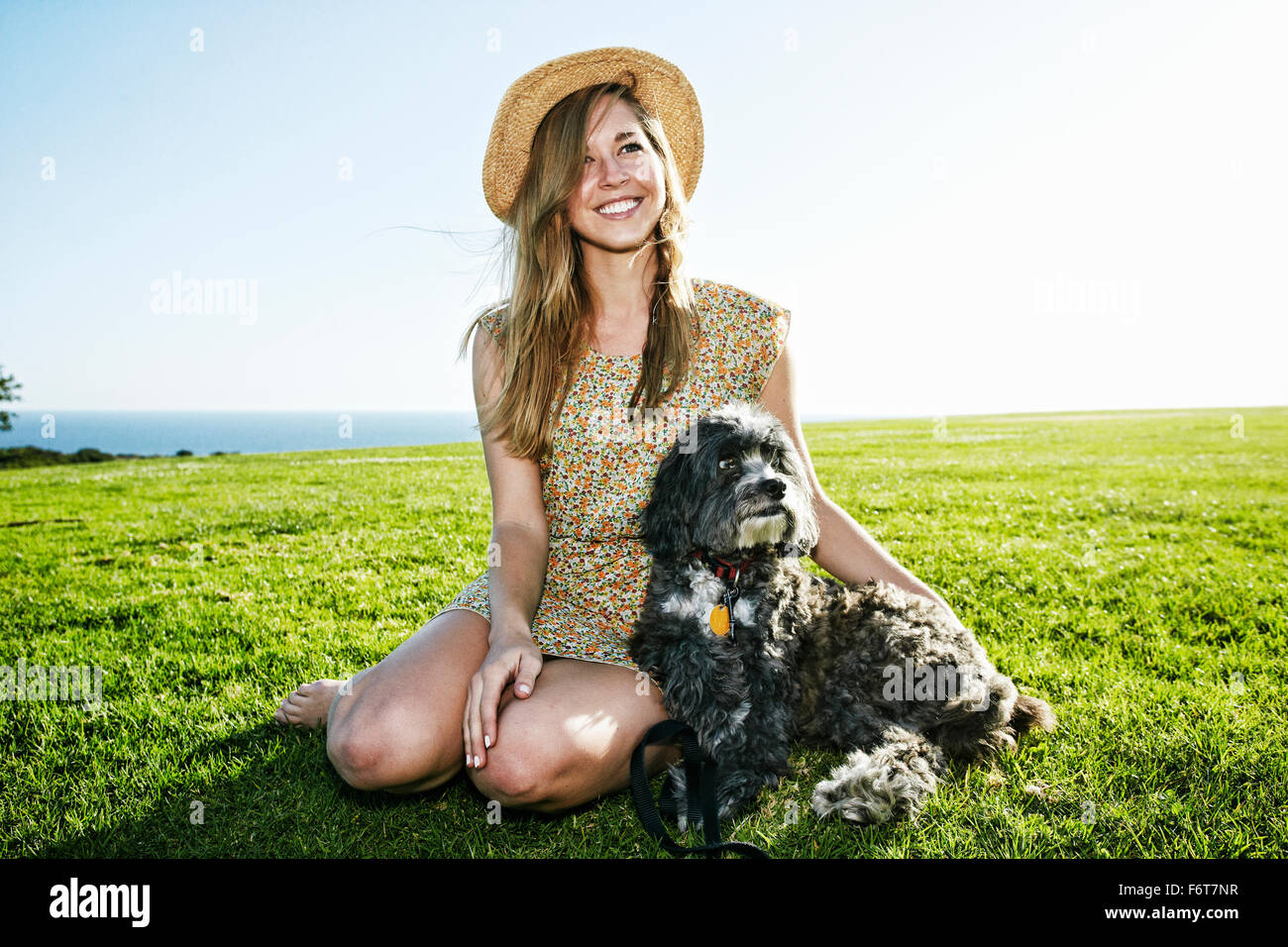 Caucasian woman sitting in field with dog Stock Photo