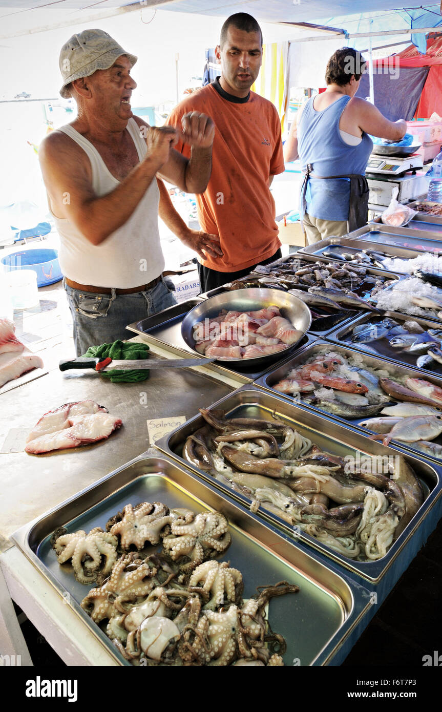 Fishmongers selling seafood and fish at the market of Marsaxlokk, Malta Stock Photo