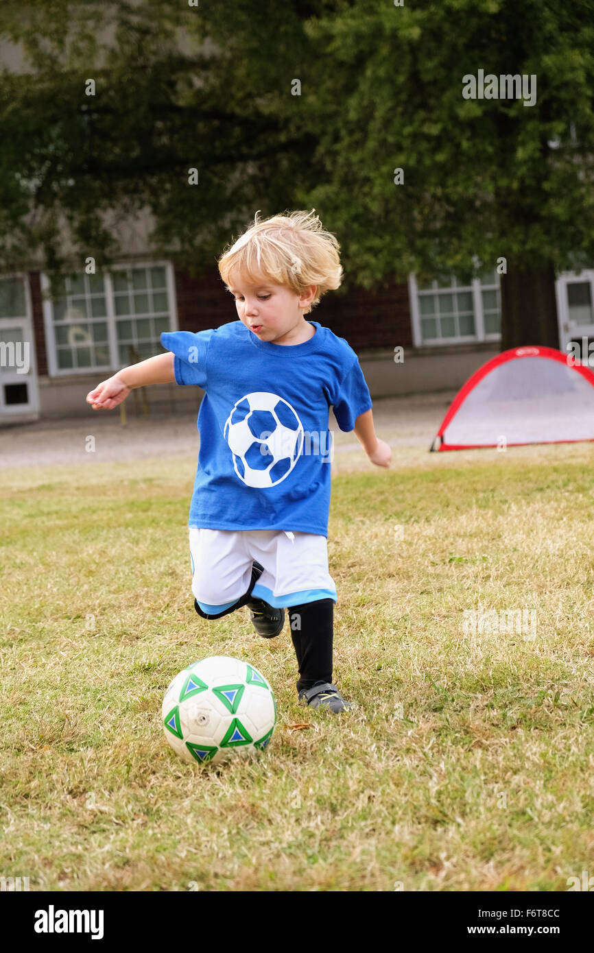 Caucasian boy playing soccer in field Stock Photo