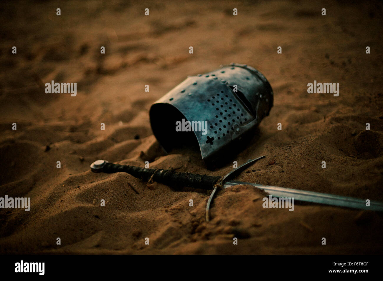 Medieval helmet and sword in sand Stock Photo