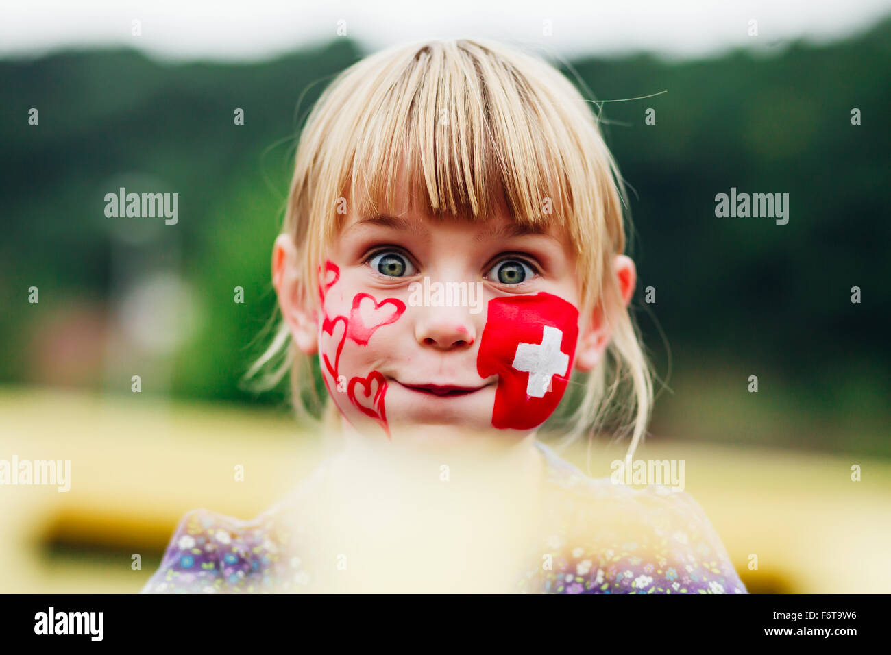 Celebrating First of August - Swiss National Day. Little girl with Swiss flag faceart. Stock Photo