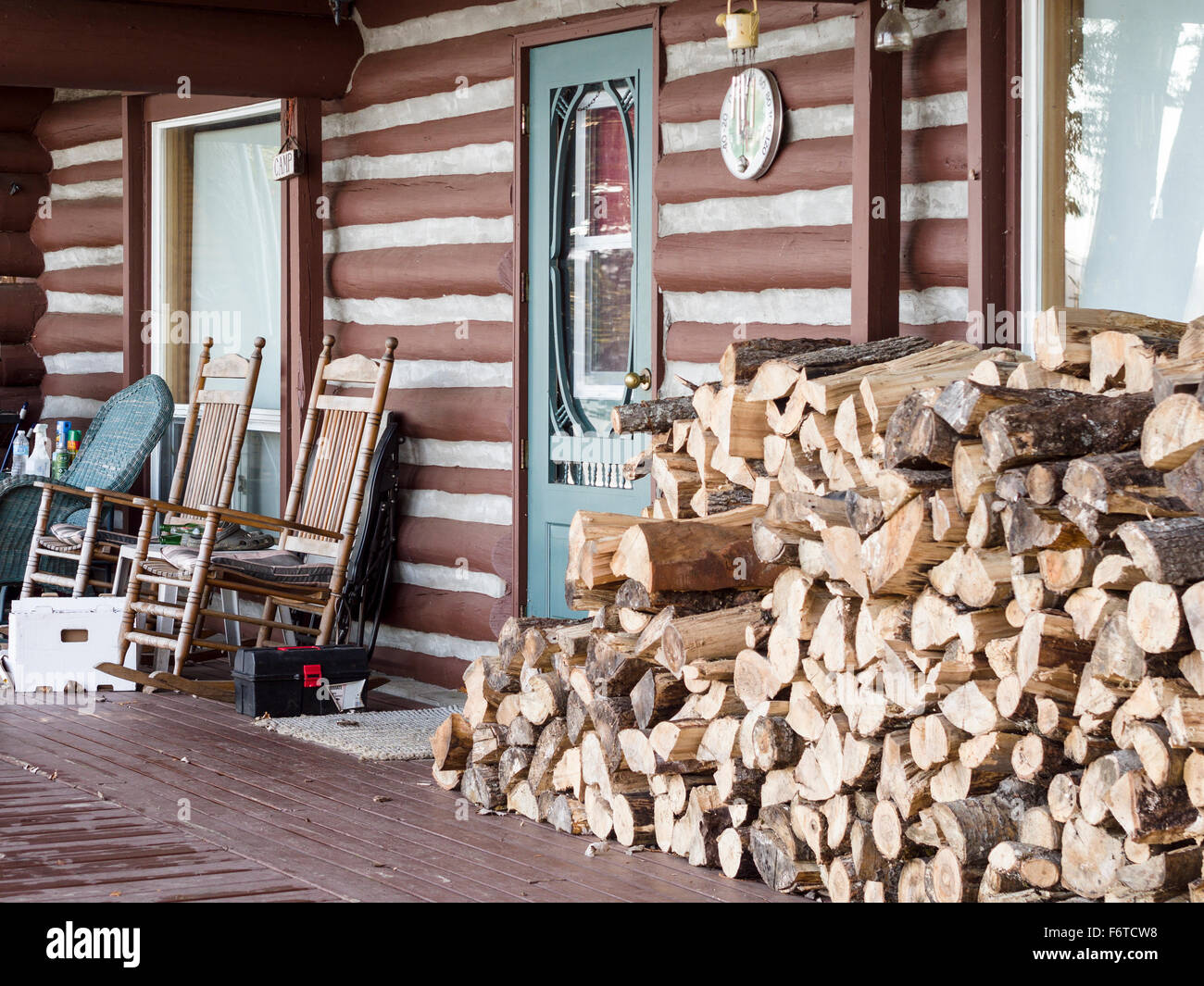 Veranda of a Cottage ready for Winter. With wood piled high and rocking chairs pushed against the wall, the front porch Stock Photo