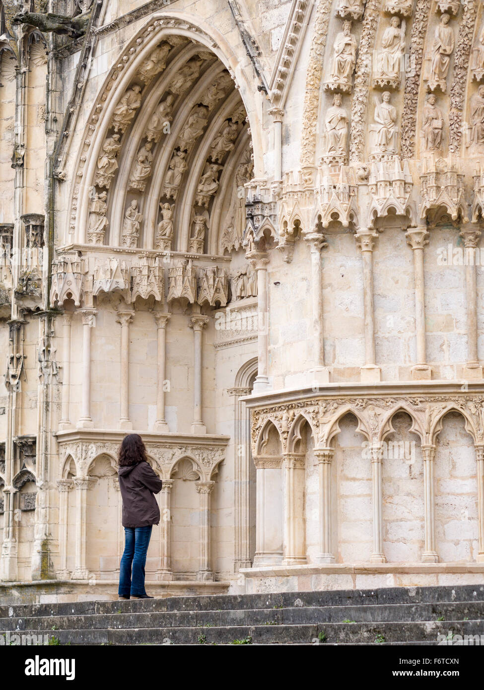 Studying the Cathedral Entrance Carvings . A woman tourist studies the carvings above a door to Bourge's Cathedral Stock Photo