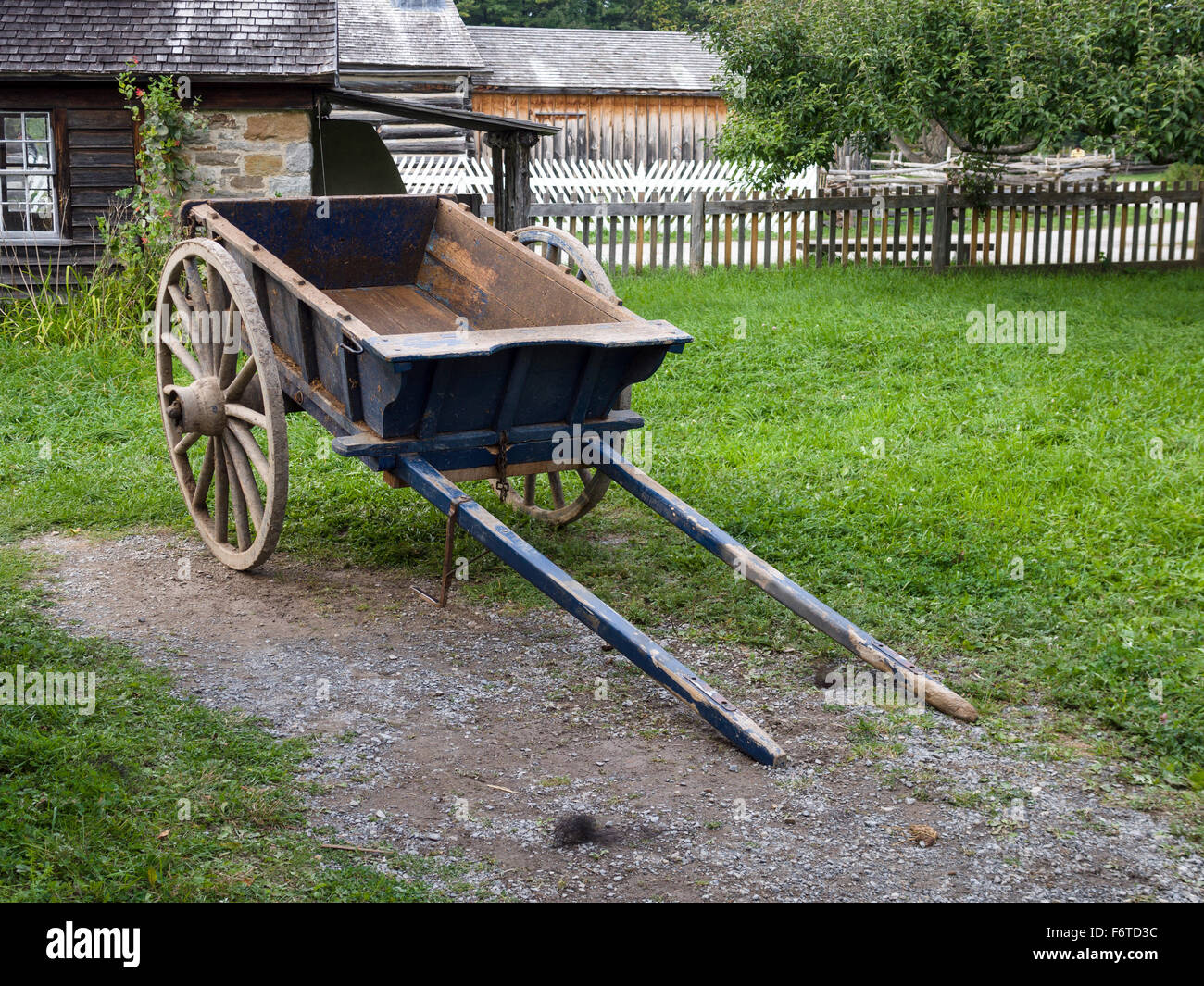 Ox Cart Parked for the Evening. A blue oxcart parked behind a house at Upper Canada Village, ready for use tomorrow. Stock Photo
