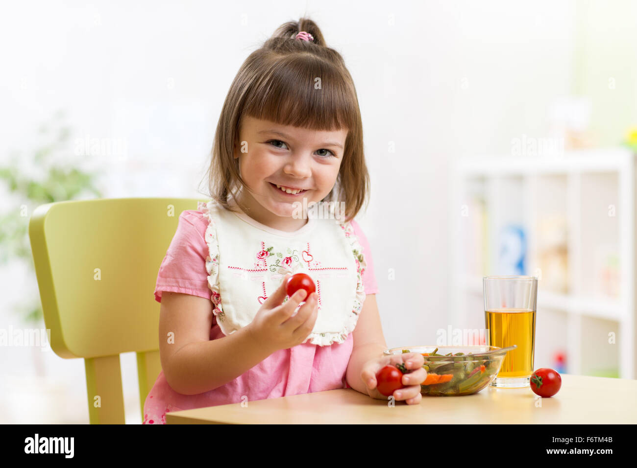 child girl eats dinner and shows tomatoes Stock Photo