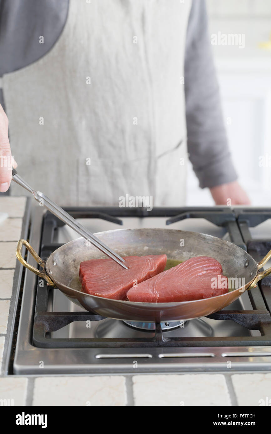 Man frying tuna steaks in pan Stock Photo Alamy