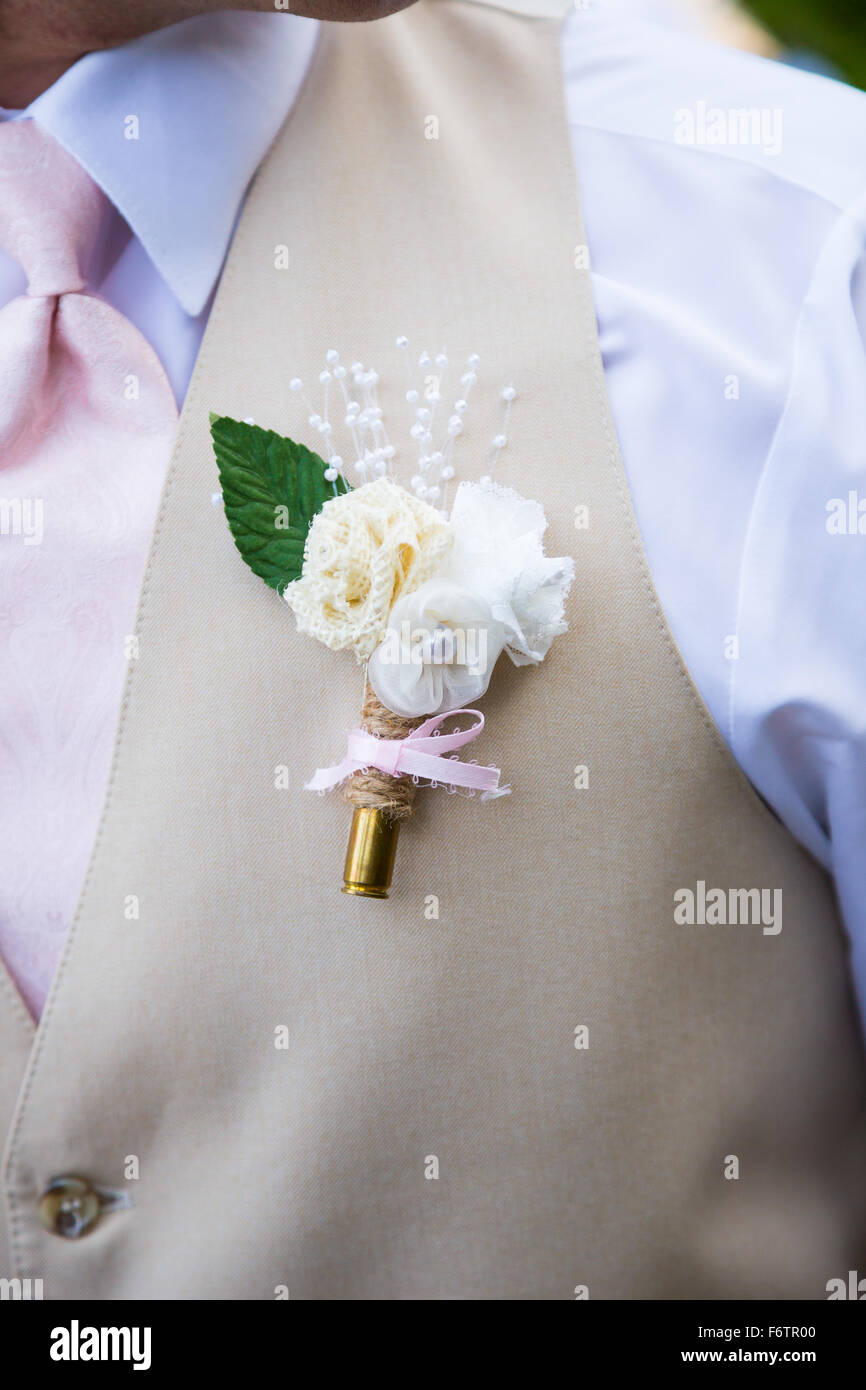 Rifle bullet cartridge with a flower attached to a groom at a wedding ceremony. Stock Photo