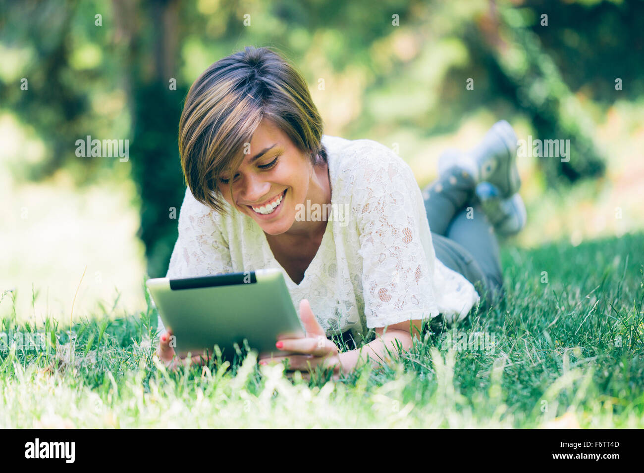 Teenage girl lying in grass looking at digital tablet Stock Photo - Alamy