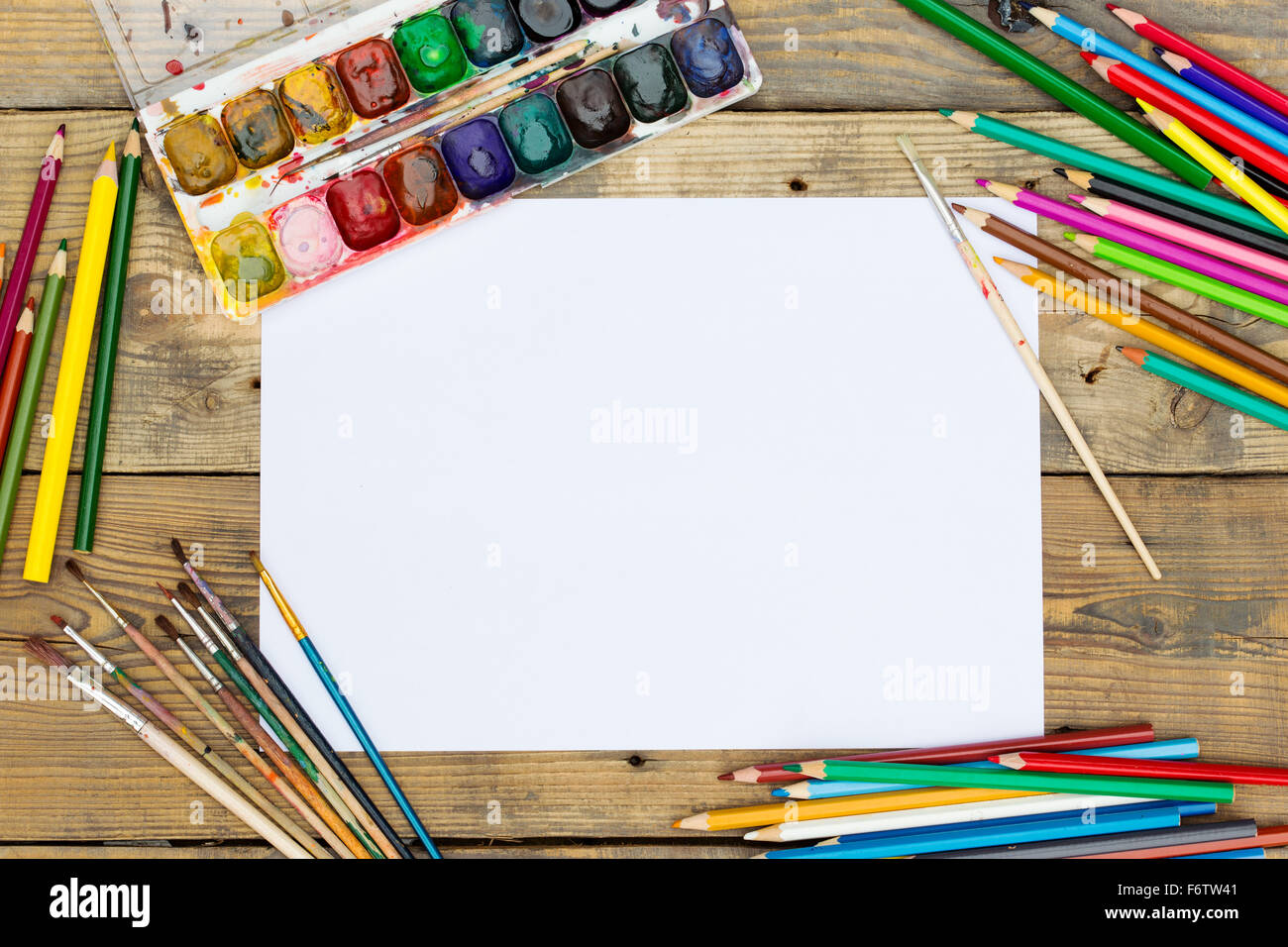 Plastic paint palette with paint and brushes on wooden table Stock