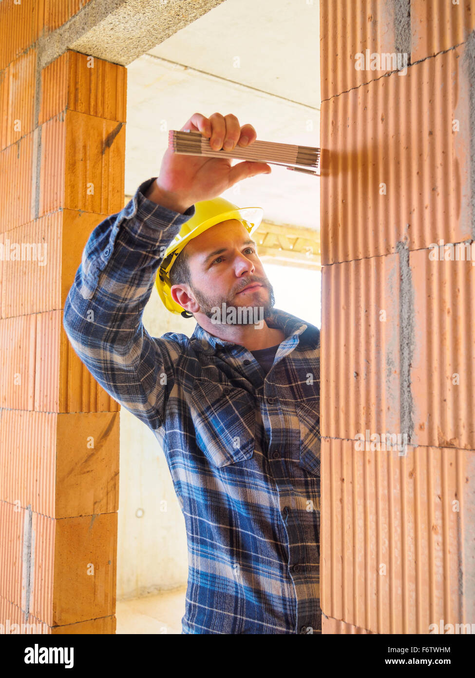 Foreman with construction plan  checking construction work with pocket rule Stock Photo