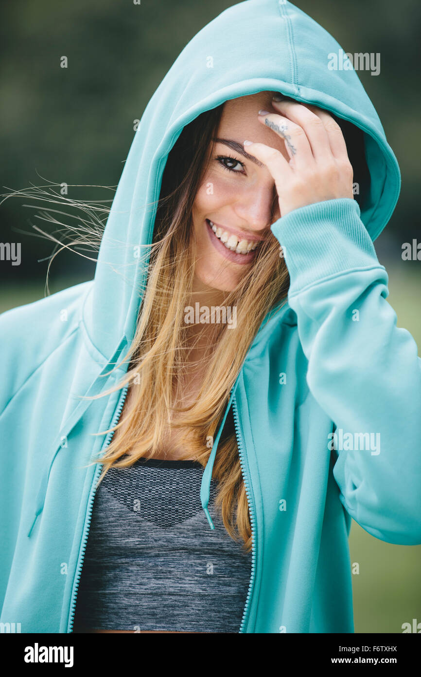Smiling sportive young woman wearing hoodie Stock Photo