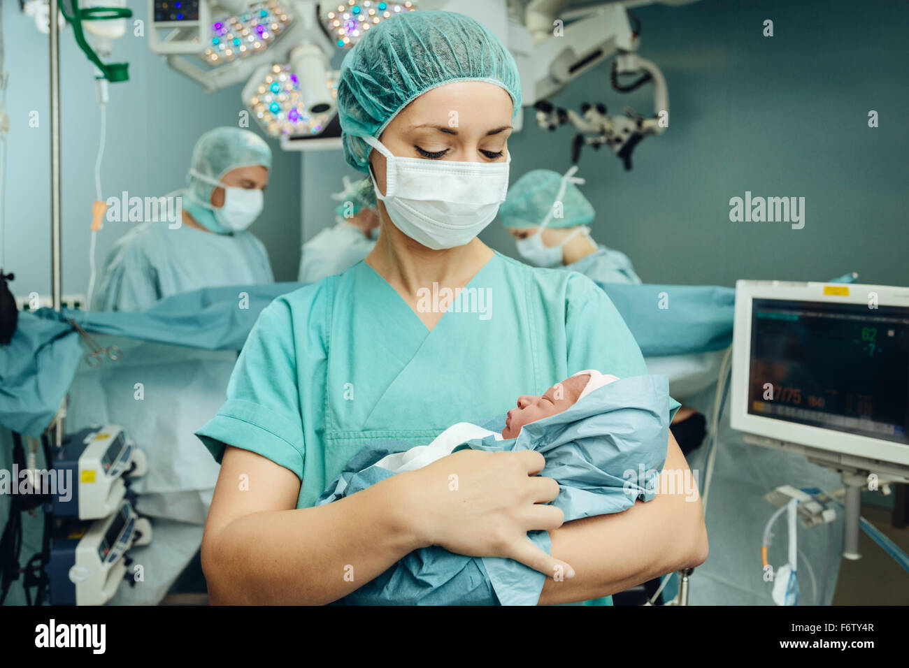 Operating room nurse holding newborn in operating room Stock Photo